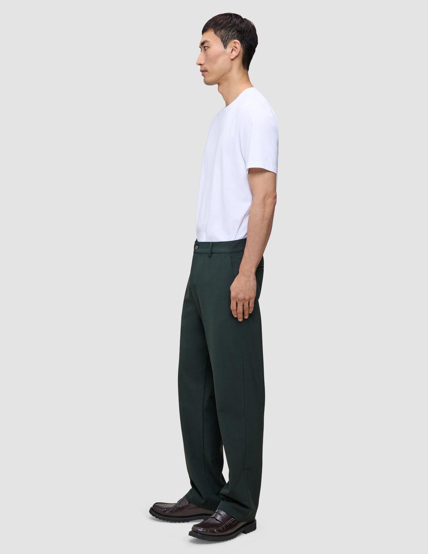En man, sedd i profil, bär en vit t-shirt och Ease Pants Relaxed Fit Northern Pine, med en skandinavisk design i avslappnad passform.